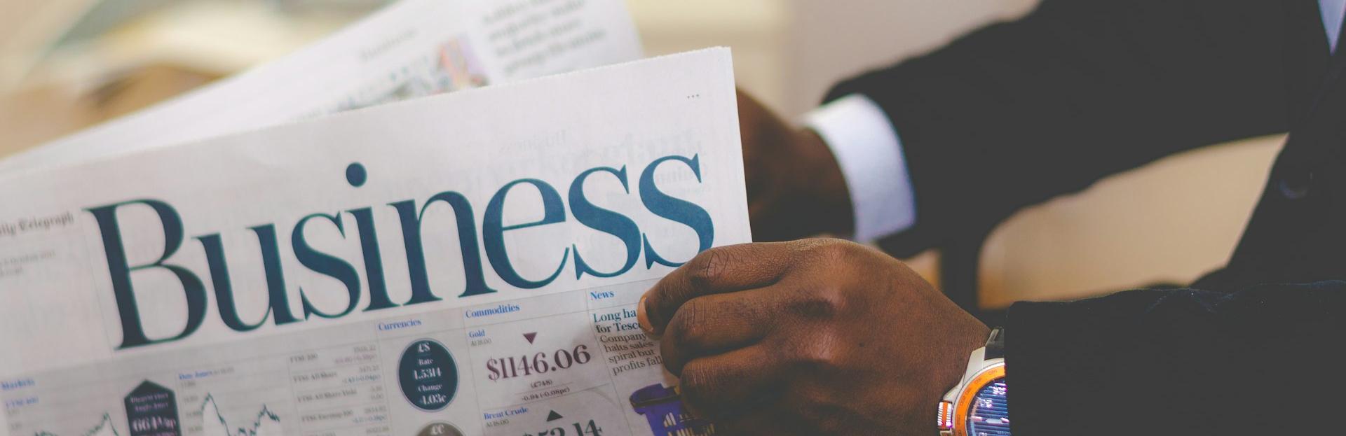 person wearing suit reading business newspaper